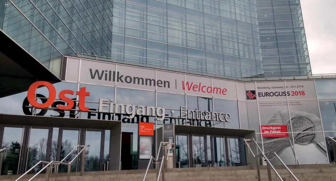 Bruschi's presence at Euroguss 2018 in Nuremberg, Germany. The image shows the entrance to the trade show, highlighting Bruschi's expertise in zinc (zamak) and aluminum die-casting components.
